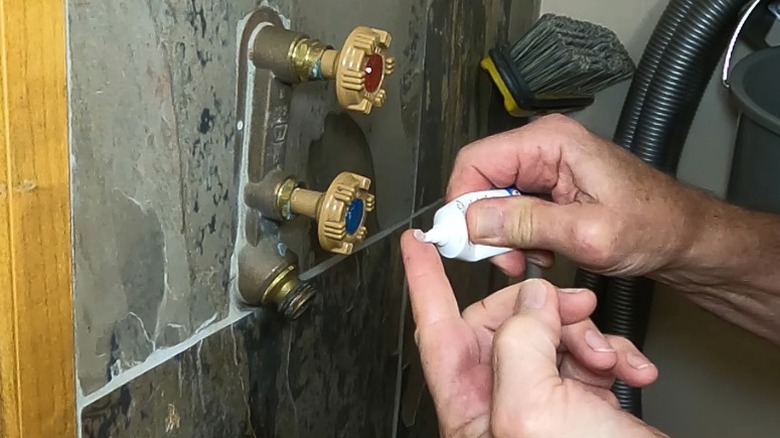 Person applying dab of silicone plumber's grease on finger to apply to hose bib