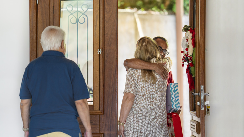 Hosts greeting a guest arriving at their home