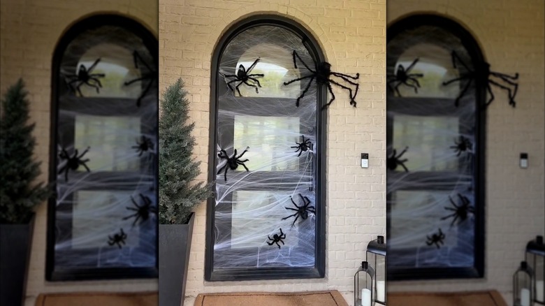 Front door covered in fake white spider-webs and black spiders for Halloween