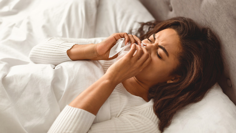 A woman holding a tissue to her nose