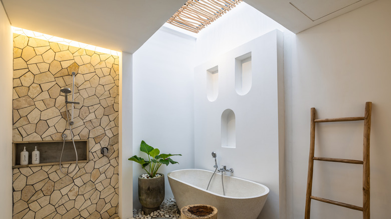 modern neutral bathroom with tiled shower and white bathtub and white walls with a skylight above