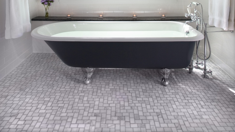 white and blue bathroom with white wainscoting on the bottom half, and a window over a tub