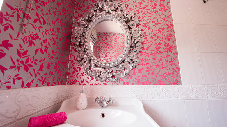 bathroom with white tile and pink and silver wallpaper as well as decorative silver mirror