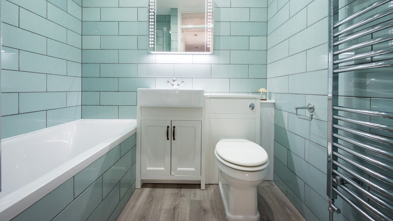 tiny aqua and white bathroom with sink bathtub and toilet crowded together