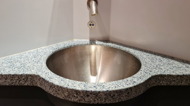 sink built into a corner with granite table top and silver hardware