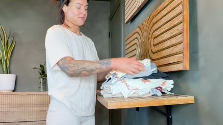 Woman folding clothes on fold-up laundry room shelves