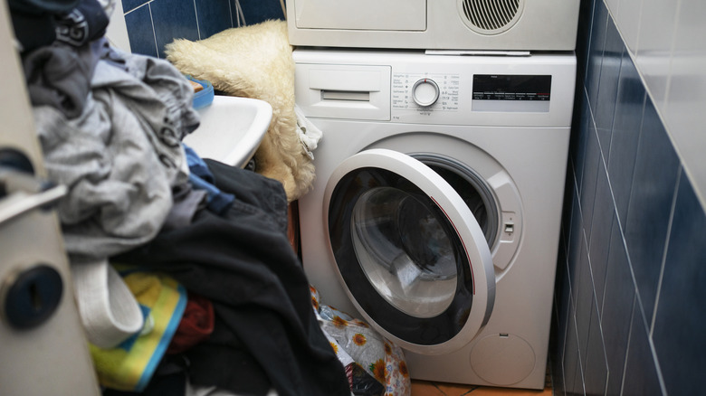 Small, cluttered laundry room with clothing scattered around