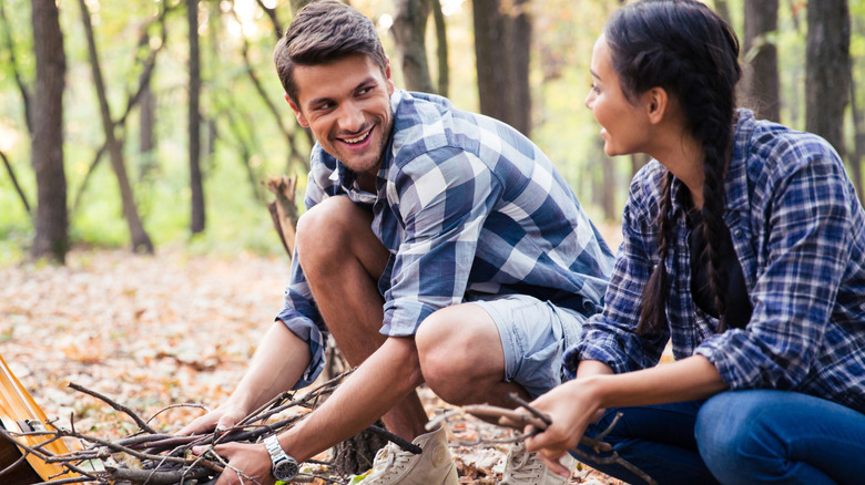 A couple gathers sticks in the woods
