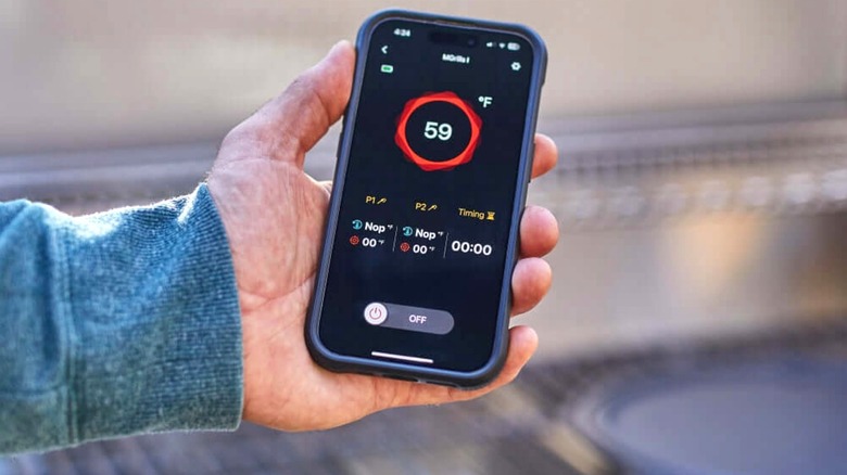 Person using a grill and the smart grilling app on their smartphone