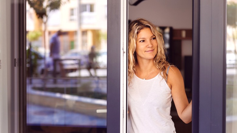 Woman standing in doorway of apartment with glass doors