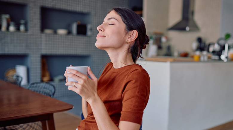 Woman with coffee relaxing in clean kitchen