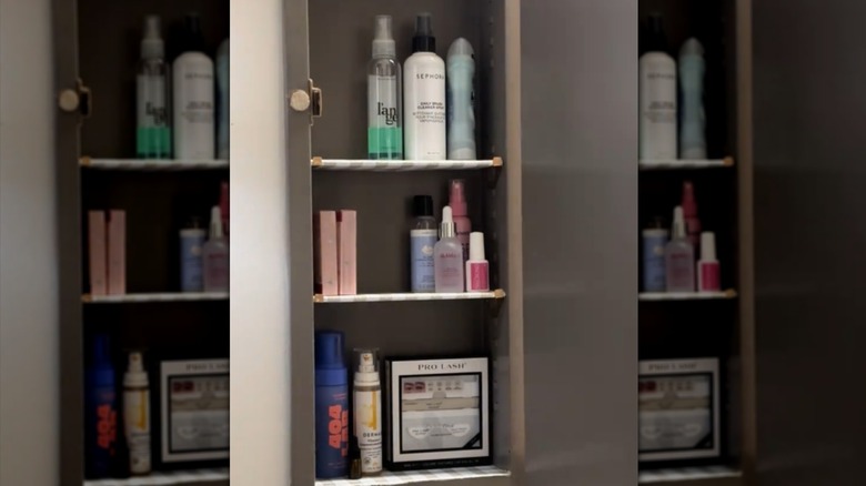 The interior of a medicine cabinet painted dark gray with striped shelf liners