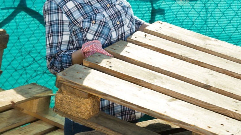 Person pulling a wood pallet from a stack