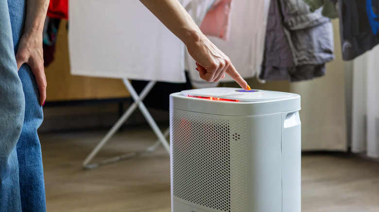 A person turning on a dehumidifier in home