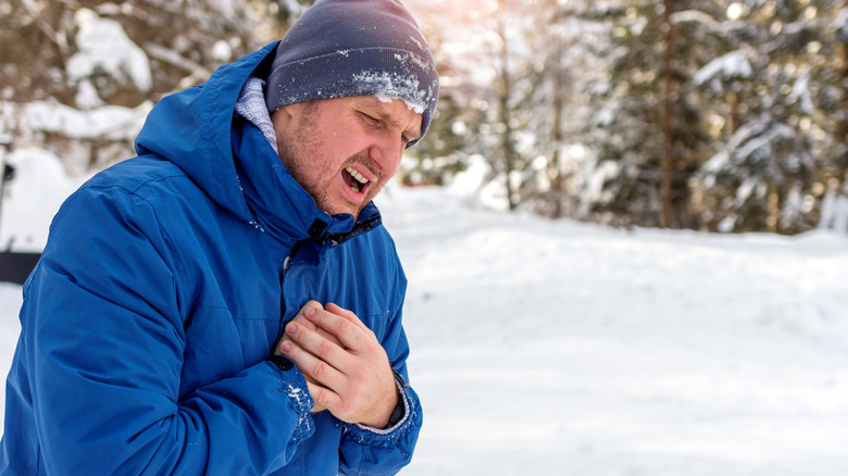 man experiencing chest pain while shoveling snow