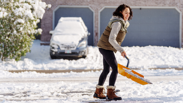woman shoveling snow from driveway
