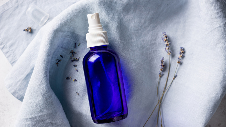 A blue bottle of DIY linen spray next to lavender
