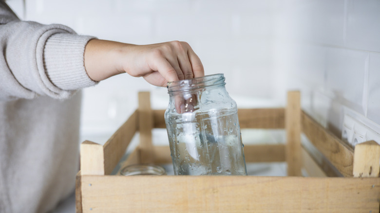 Person reaching for an empty glass jar on the counter