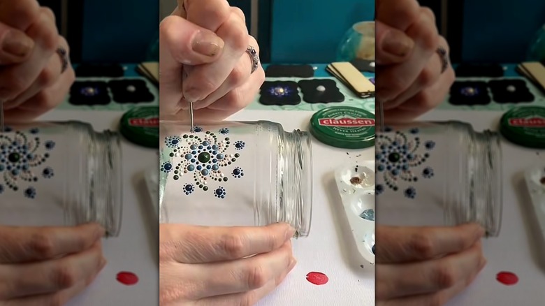 Person handpainting dot art onto an old pickle jar