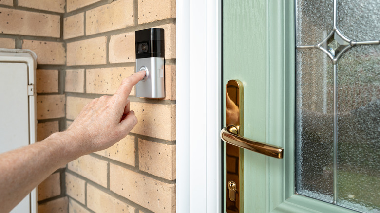 A person's hand ringing a video doorbell
