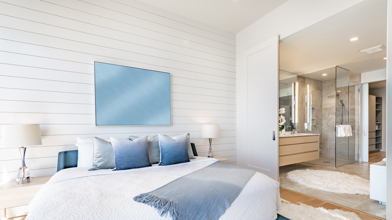 A bedroom wall with shiplap in front of an ensuite bathroom