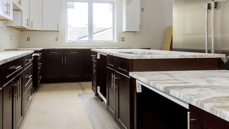 A light-filled kitchen has dark brown lower cabinets