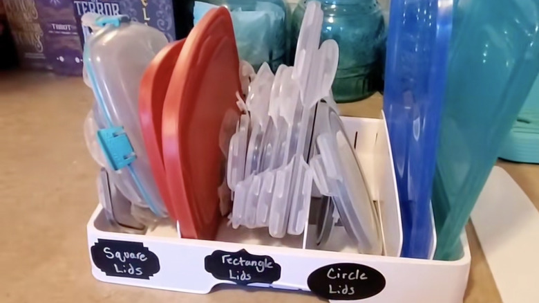 Plastic food container lid organizer on a countertop with labels on it