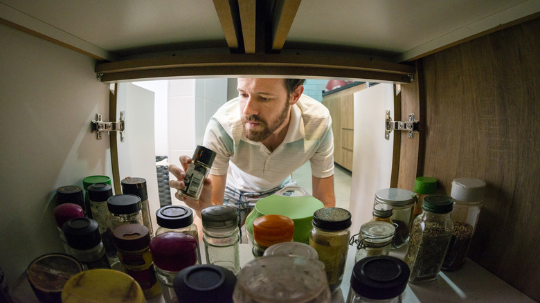 Man searching for items in a deep shelf
