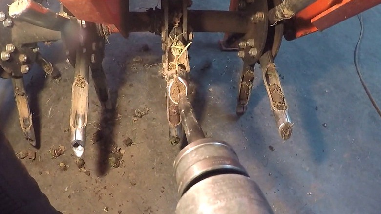 Person clearing out lawn aerator tines with a chisel bit in a pneumatic tool