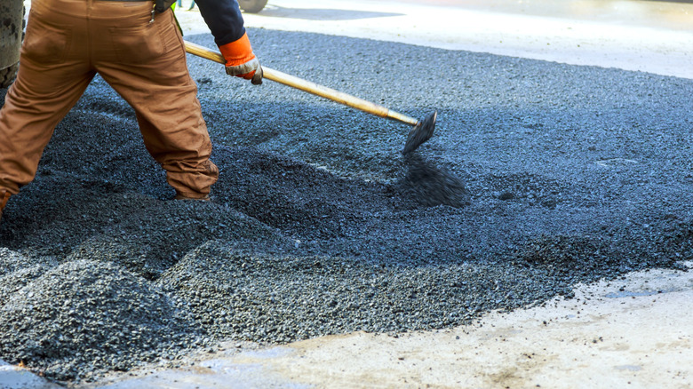 Worker spreads asphalt on driveway