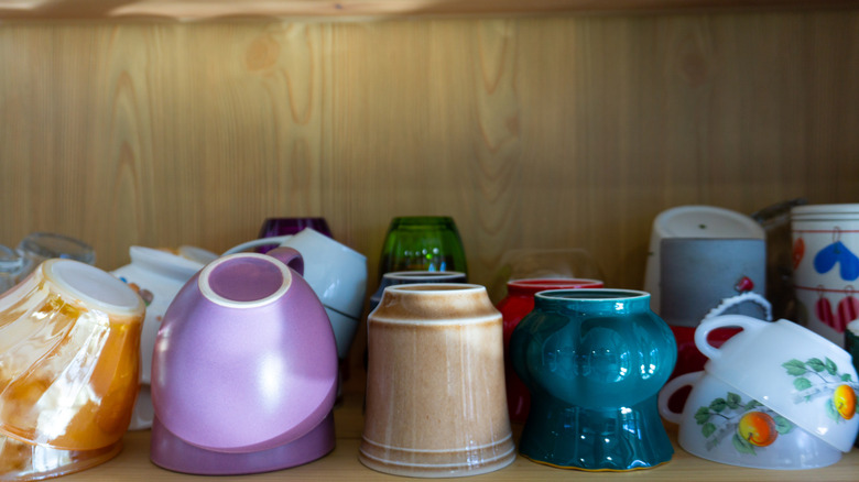 mugs in a crowded kitchen cabinet