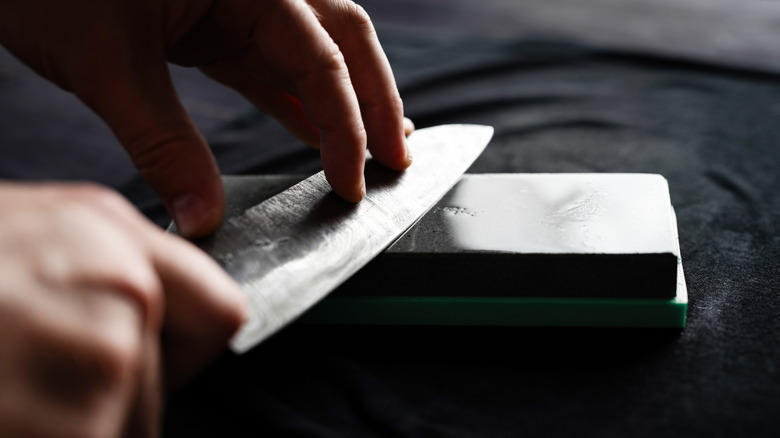 Man sharpening knife on whetstone