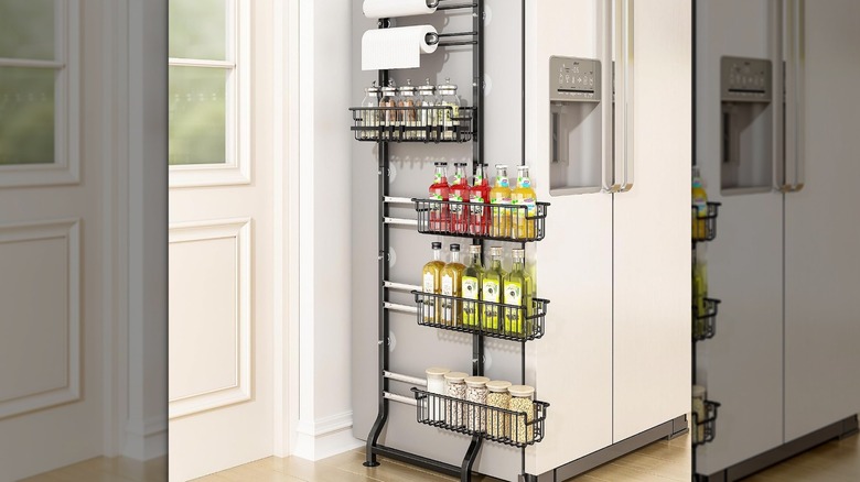 A black six-tier spice rack with items next to a fridge in the kitchen