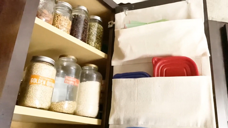 Off-white canvas lid storage pouch hanging on the inside of a cabinet door on Command hooks