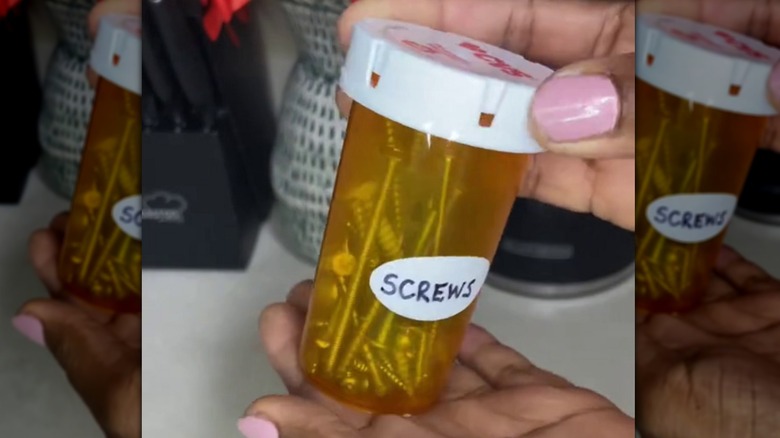 Woman holding labelled orange prescription bottle filled with screws