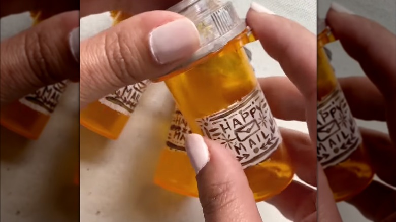 Woman holding pill bottle with cute mail label for shipping miniature items