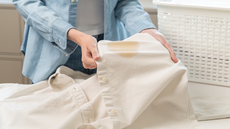 a person holds a stained white shirt
