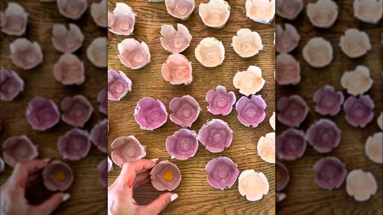 A display of multiple hand-painted flower-shaped egg carton cups in spring colors