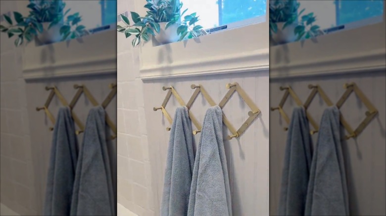 Accordion hook hanging on a bathroom wall with two blue towels hanging from it