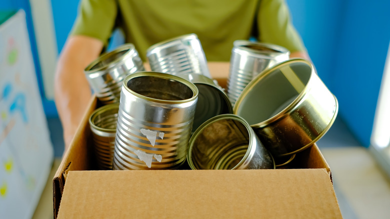 Man carrying box of tin cans
