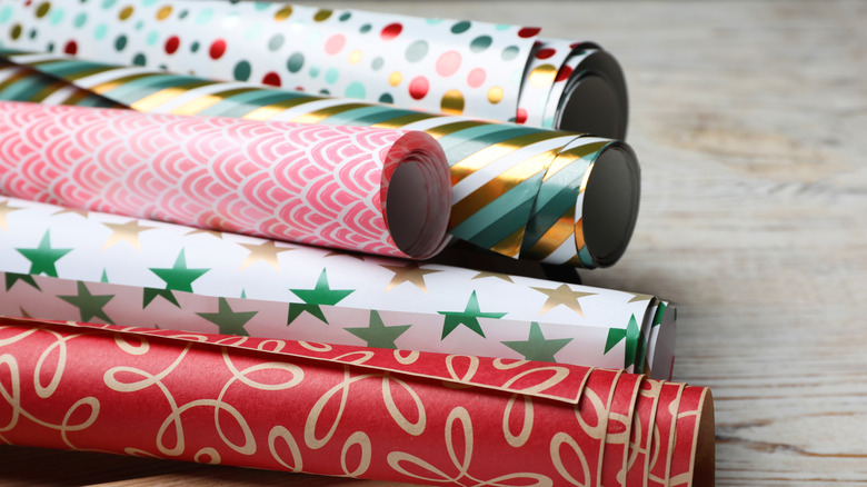 Assorted festive and colorful wrapping paper rolls on wood table