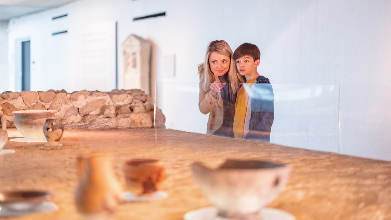 A woman shows her son ancient artefacts at a museum