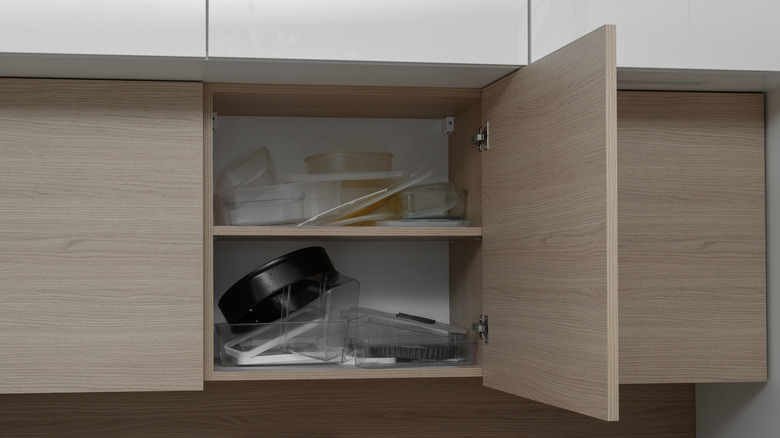 Disorganized piles of plastic container lids in a cabinet