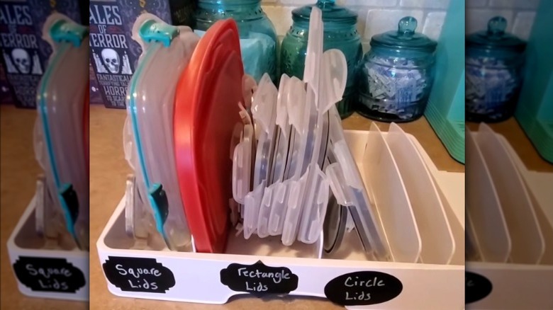 Plastic food container lid organizer on a countertop with labels on it