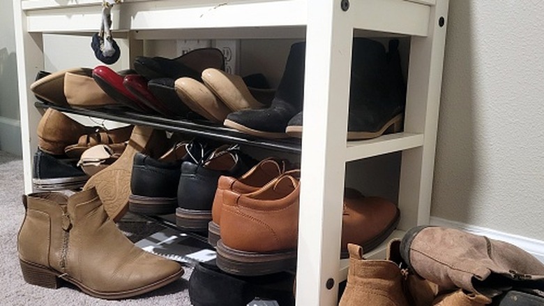 A large collection of shoes overflowing from a shoe rack.