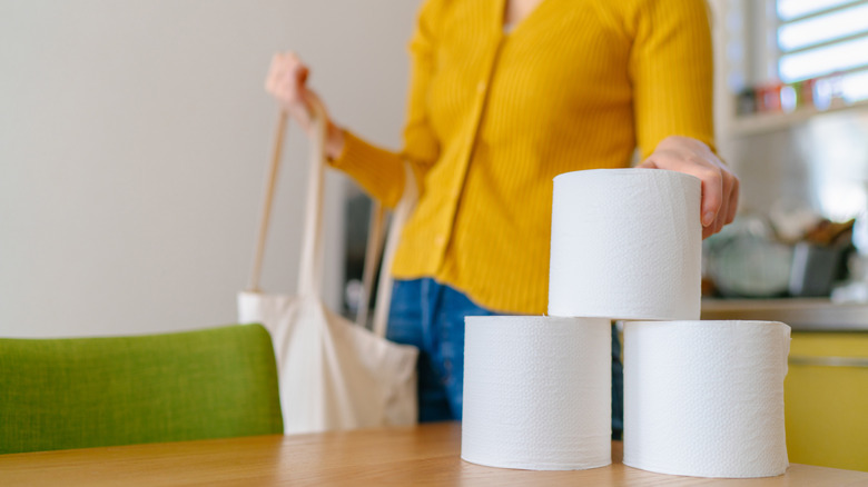 A person reaching for a stack of toilet paper