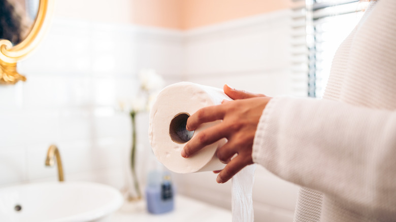 Woman holding toilet paper roll in a bathroom