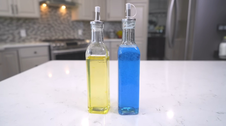 A woman takes two glass oil and vinegar bottles off the shelf at Dollar Tree