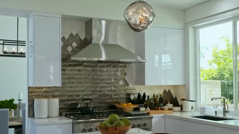 A white kitchen with a silver subway tile and white arabesque tile backsplash