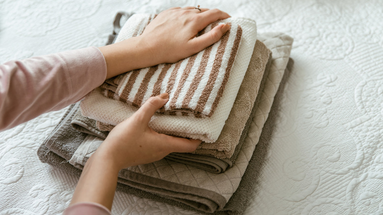 Person folding a stack of small and large bathroom towels